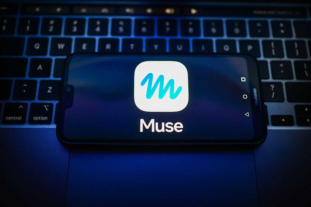 A Meta Muse logo is displayed on a smartphone on the top of a laptop.