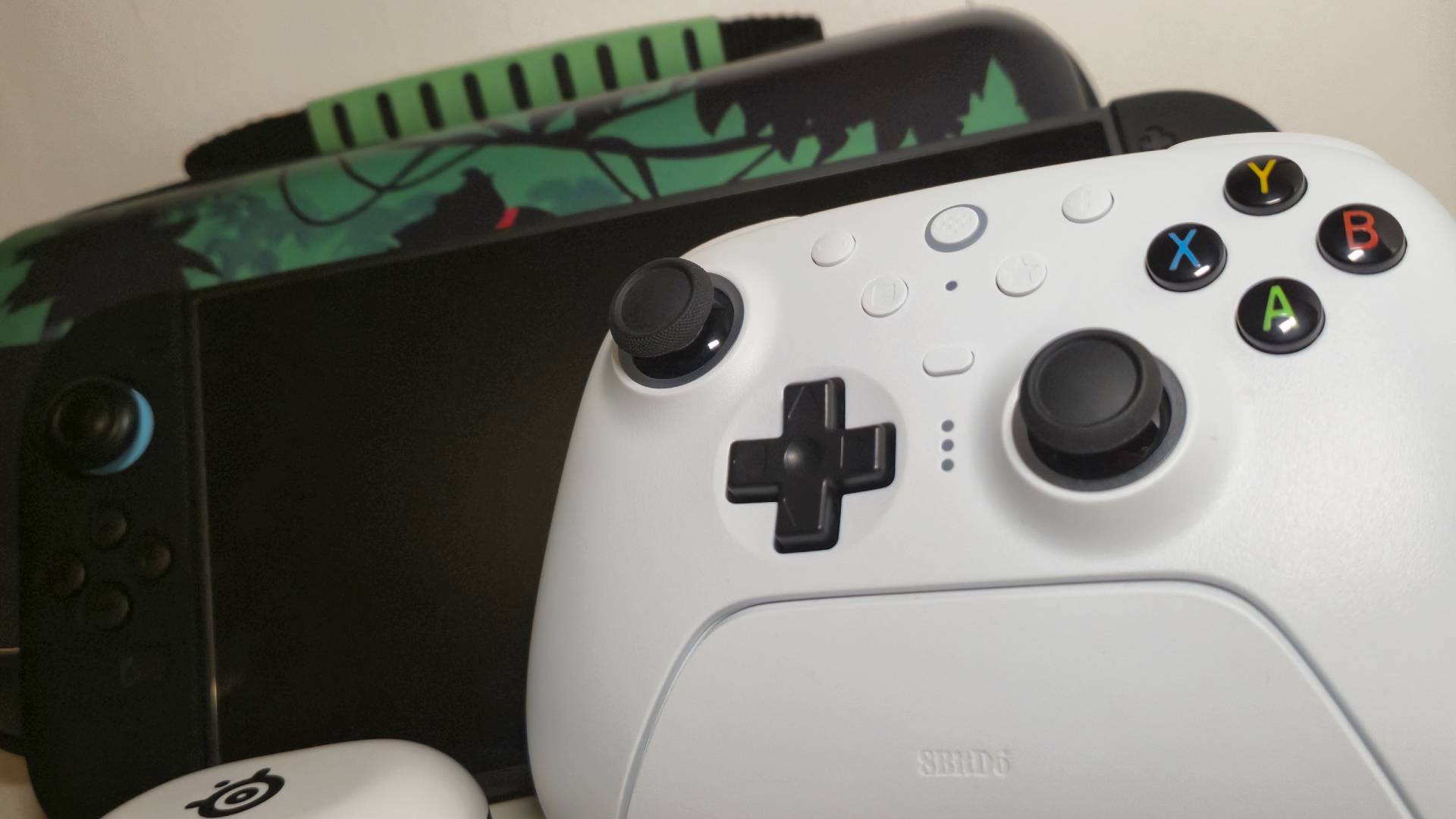 Photo of a bunch of Switch 2 accessories together, including a white 8Bitdo Ultimate 2 controller and Donkey Kong case.