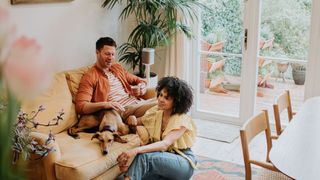 A couple sitting on a couch with their dog