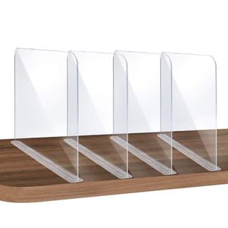 Four clear shelf dividers on a wooden shelf