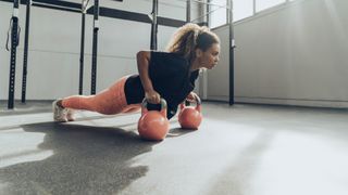 Young woman exercising with kettlebells in gym