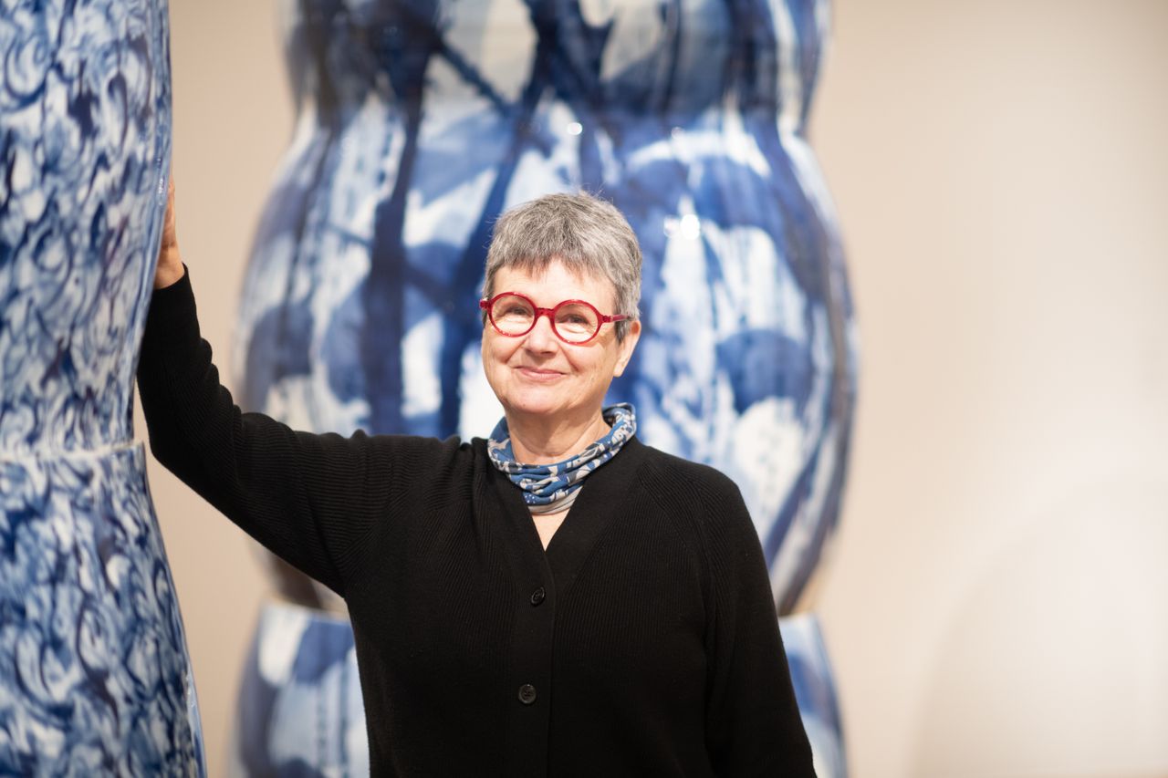 A series of gigantic china-style vases is on display in a warmly lit gallery, including some blue and white pieces and some more widely colored ones.