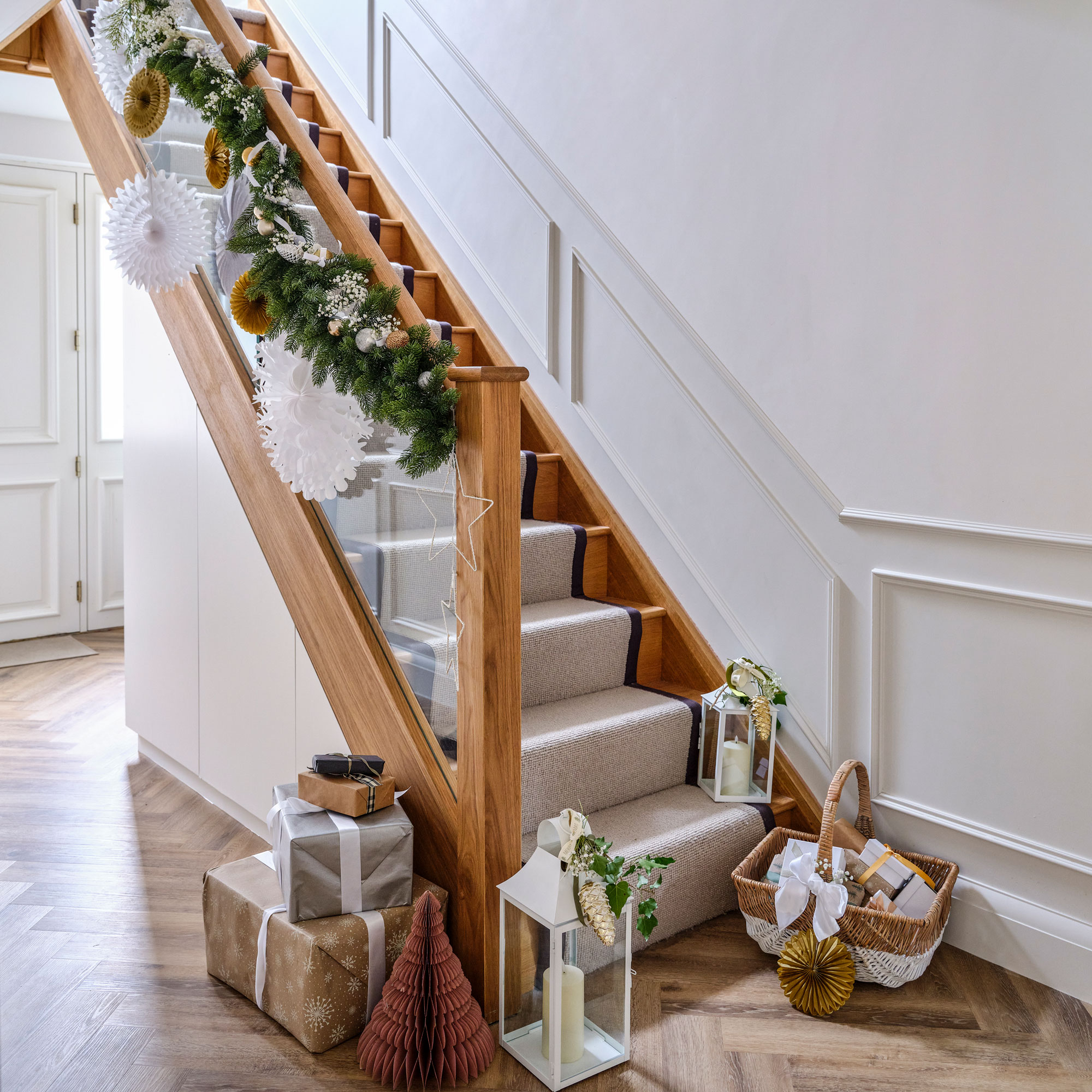 White hallway with wooden staircase with cream runner and christmas decorations