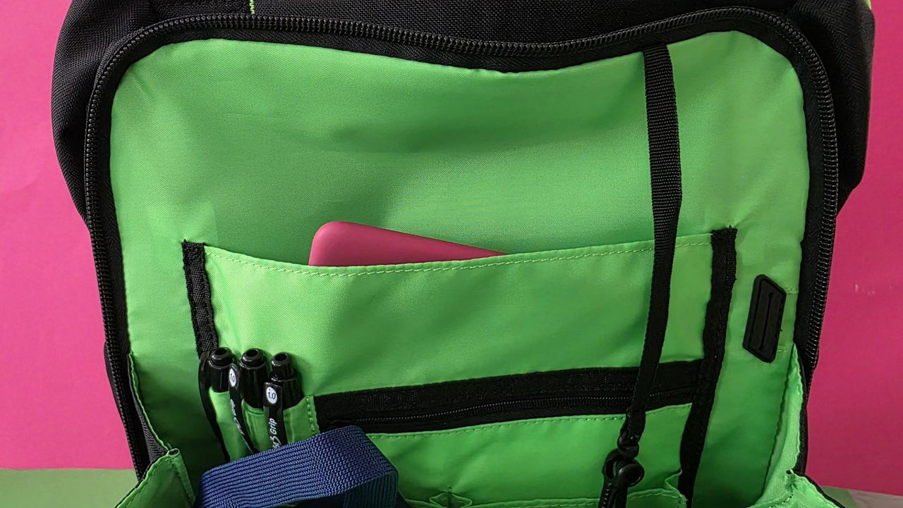 A black Razer backpack front pocket held open, contains pens.
