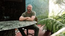 Richard Christiansen sitting at a green marble table with ferns in the foreground