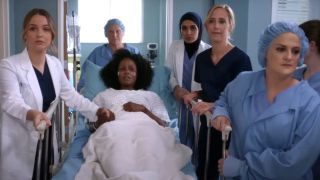 Jo (Camilla Luddington), Teddy (Kim Raver) and a nurse (episode writer Elisabeth Finch) wheel a patient down the hall through the wall of women on Grey's Anatomy's Season 15 episode "Silent All These Years."