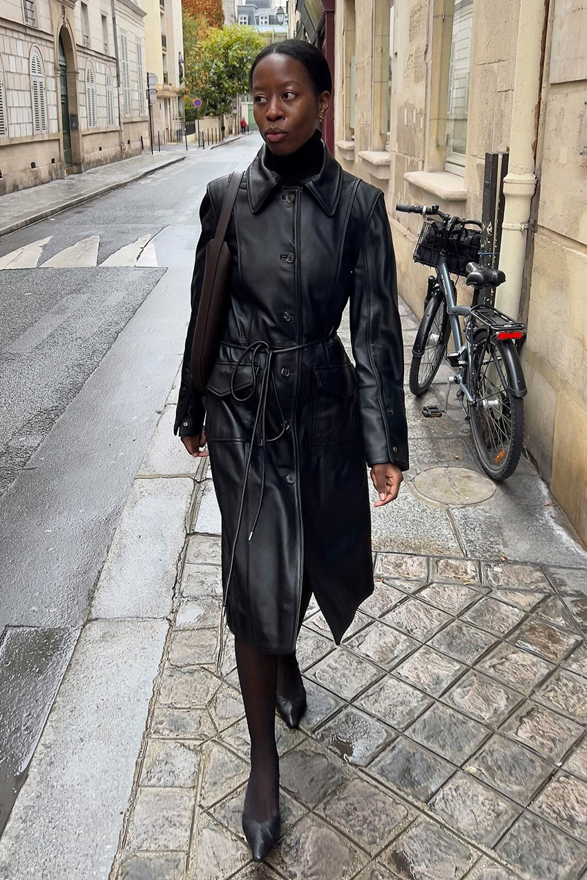 Woman wearing a black coat and brown bag.