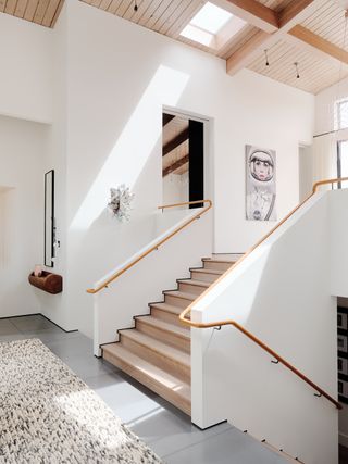 A white-walled staircase with a leather handrail