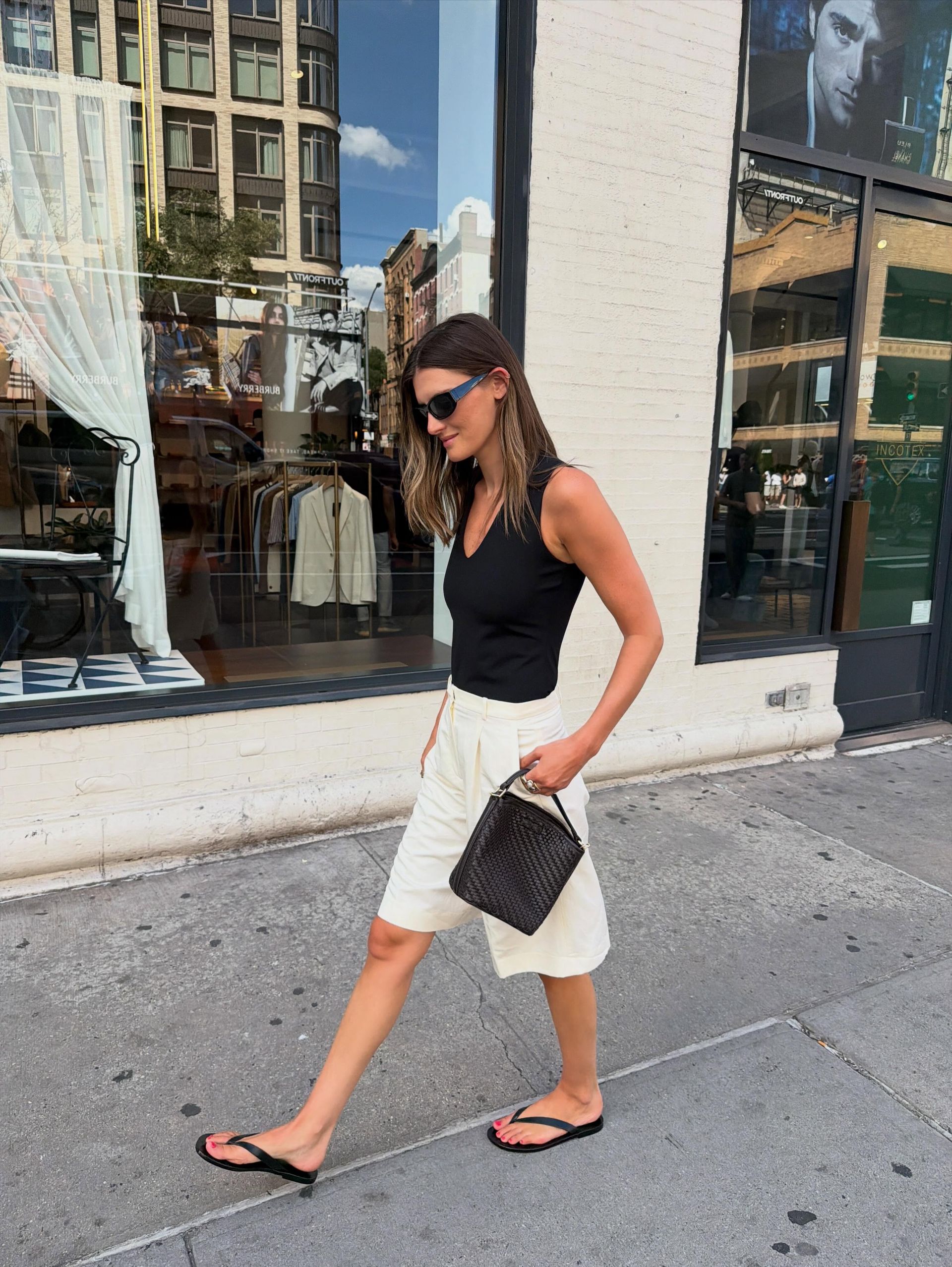 Influencer @cocoschiffer wears Bermuda shorts with black flip-flops and a v-neck tank top.