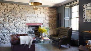 Chesterfield chairs in a living room with exposed stone wall