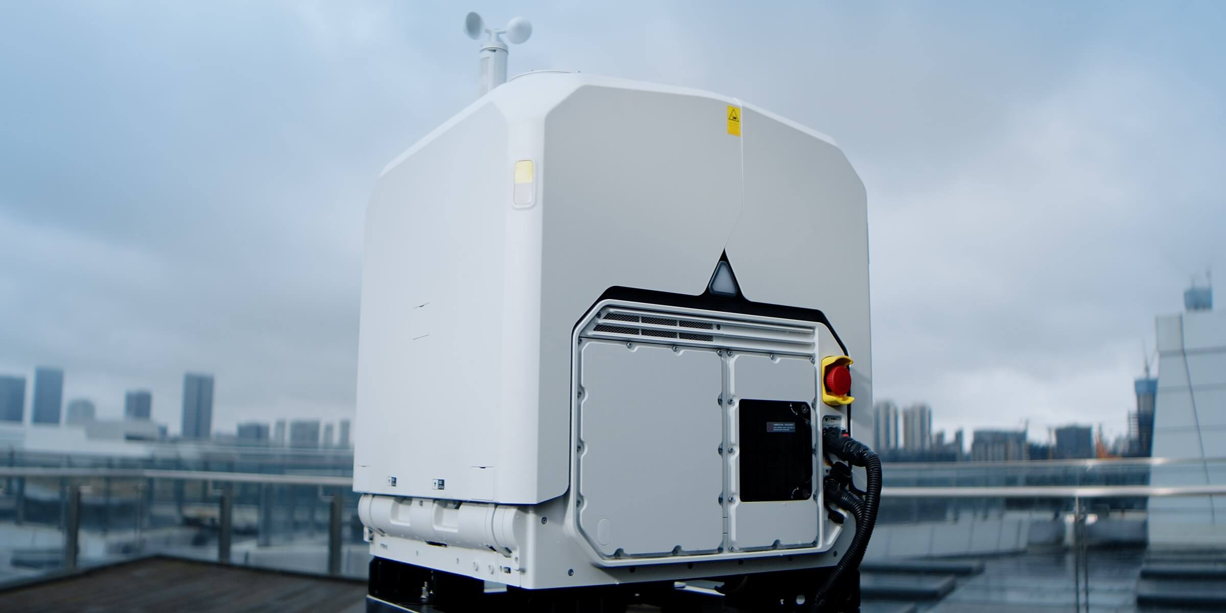 DJI Dock 4 drone dock, closed, on a rooftop with a city skyline behind it