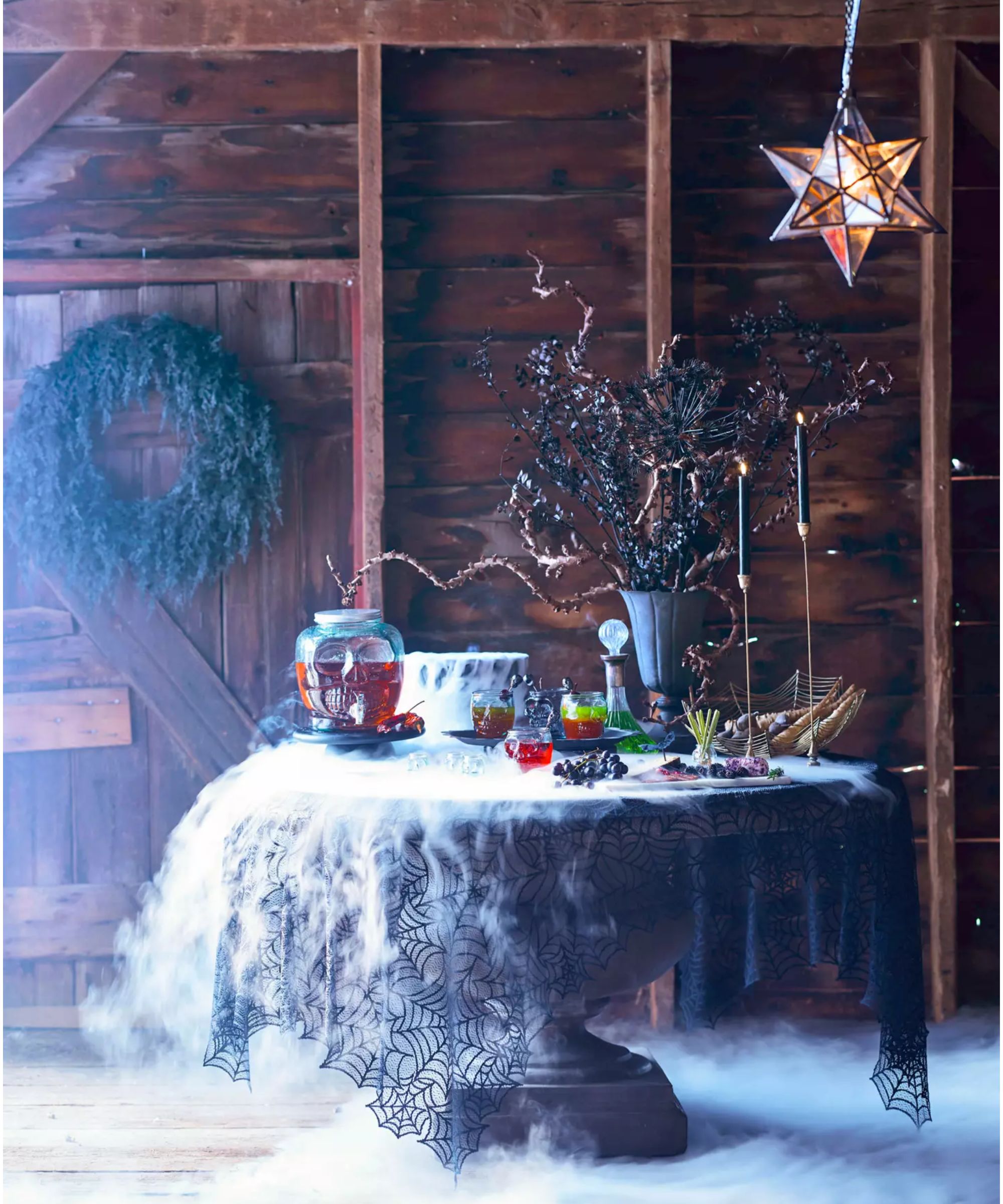 halloween pedestal table decorated with smoke, lace cobweb cloth, wreath and candles