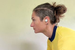 This image shows the Adidas FWD-02 headphones in ear of a rider looking forward wearing a yellow jersey.