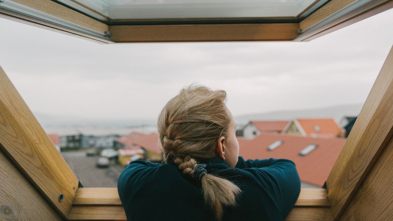 Woman looking out of a building through an open window