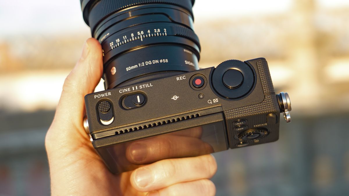The Sigma FP2 mirrorless camera in user's hand, at golden hour outdoors, with a close up of the top controls