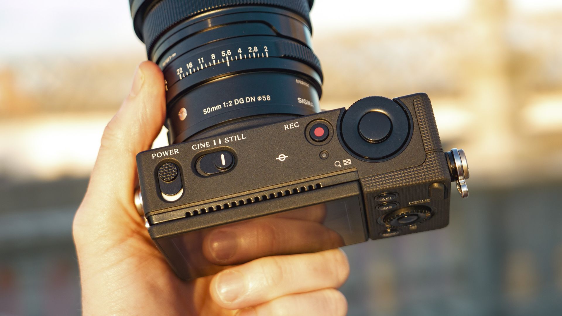 The Sigma FP2 mirrorless camera in user's hand, at golden hour outdoors, with a close up of the top controls