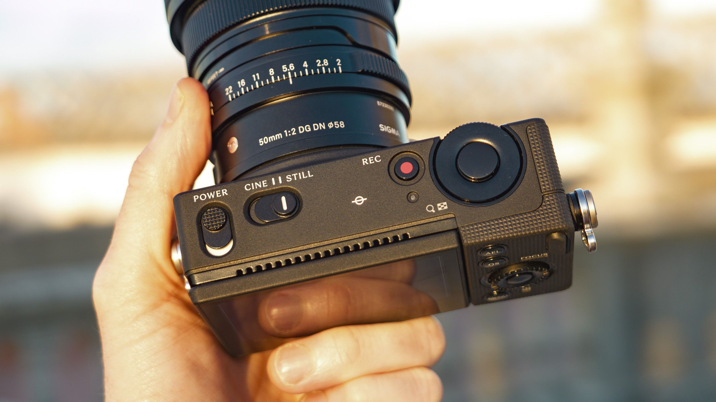 The Sigma FP2 mirrorless camera in users hand, at golden hour outdoors, with a close up of the top controls