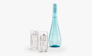 View of HeavenSake’s new Junmai Ginjo drink - The bottle is blue with a design similar to a water drop and there are two tall, filled glasses with ice pictured against a light grey background