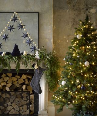 A living room with plaster wall decor, Christmas tree, felt garland, mantel decor and fireplace with firelogs