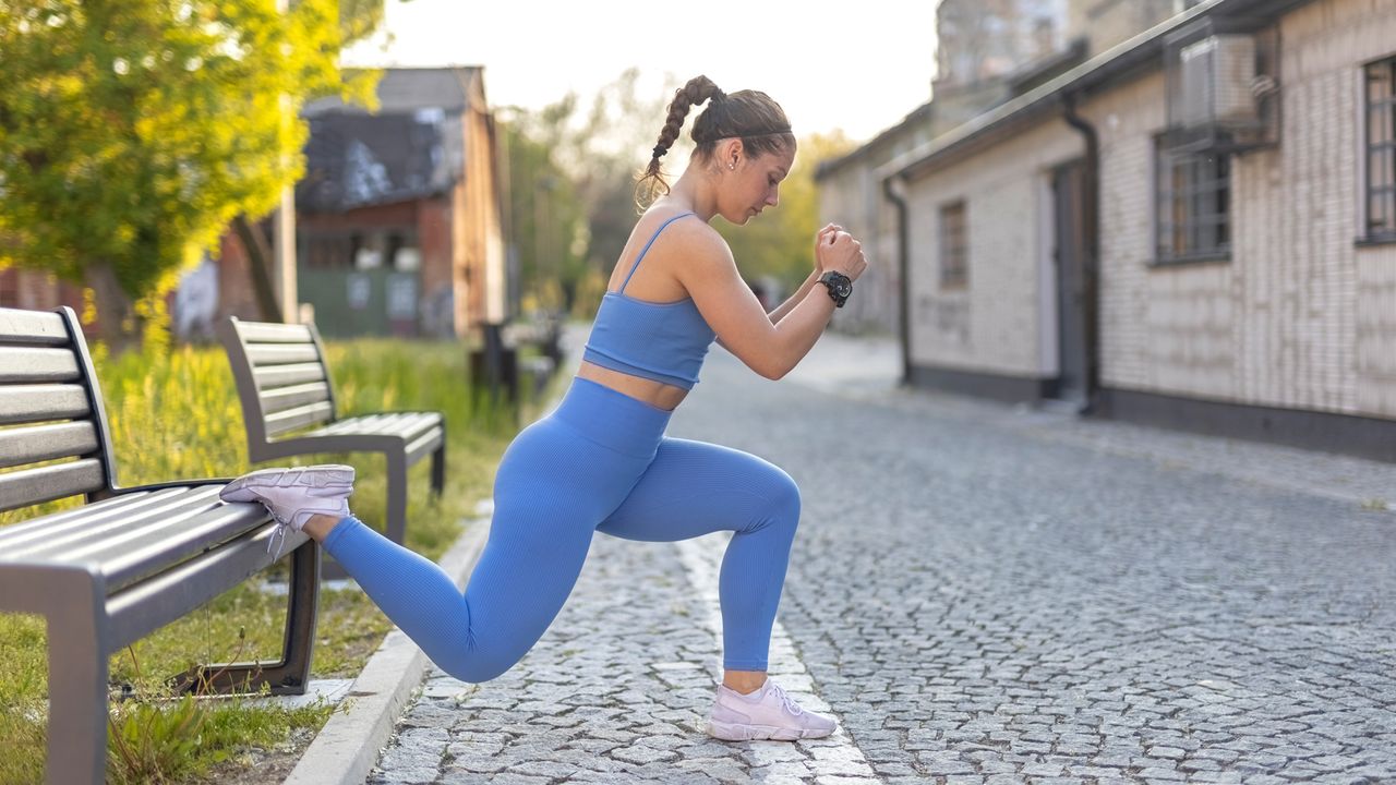 Woman performs split squat using a bench outdoors