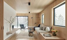 A living room clad in white oak, with a white fireplace wall and built-in bench seating
