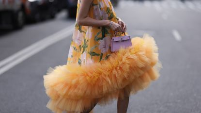 Leonie Hanne seen wearing a yellow tulle flower dress by Carolina Herrera, pink glitter heels and a Hermes mini kelly before the Carolina Herrera show on February 13, 2023 in New York City