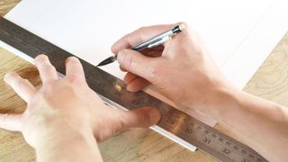 How to mount your artwork: A person marking the aperture of a board with a pencil and ruler