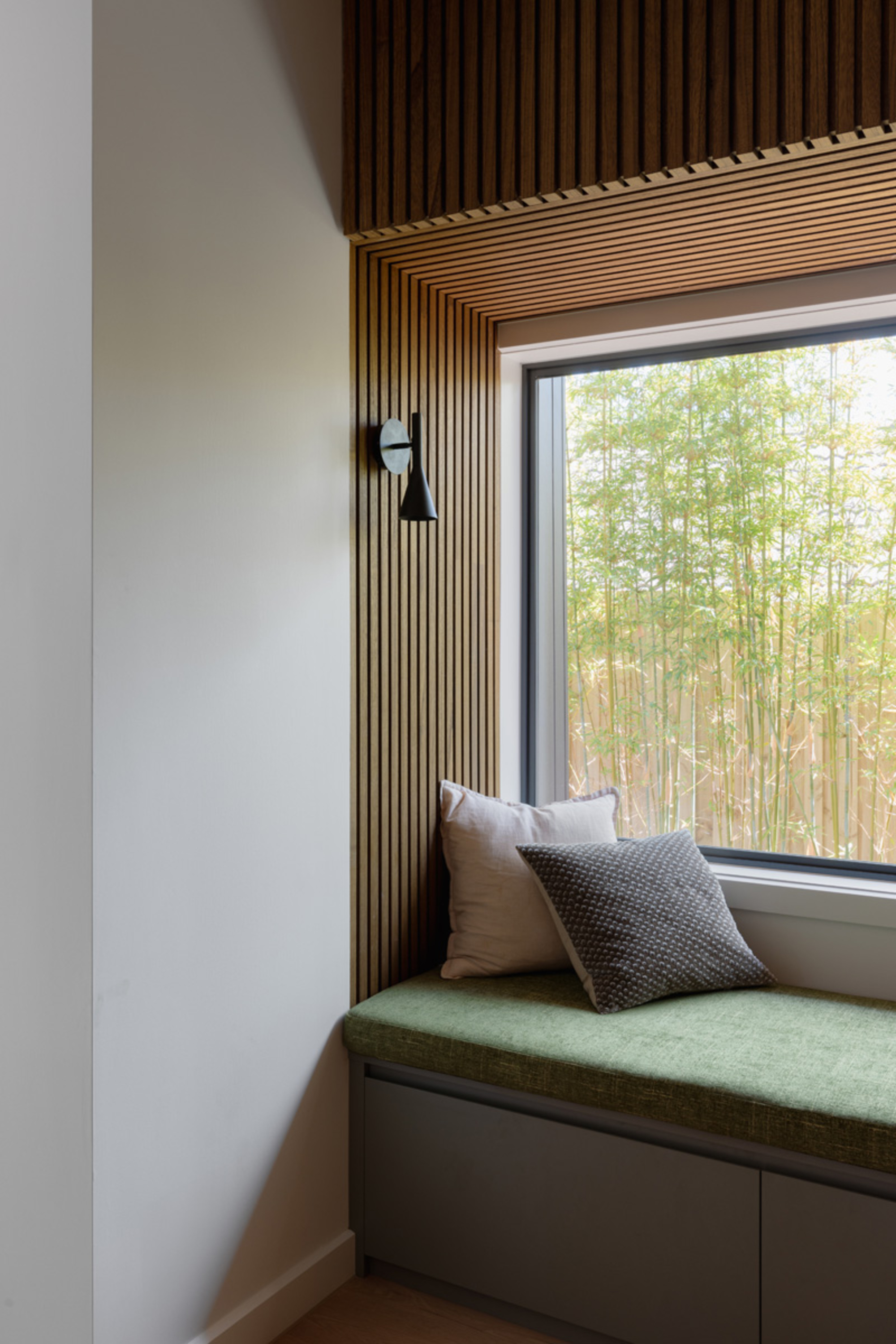 modern window seat with timber panelling, green seat cushion, large window, and downlight