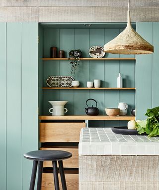 green wood panelled kitchen with tiled countertop and open shelves