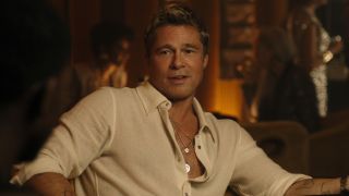 Brad Pitt sits smiling at the card table in F1.