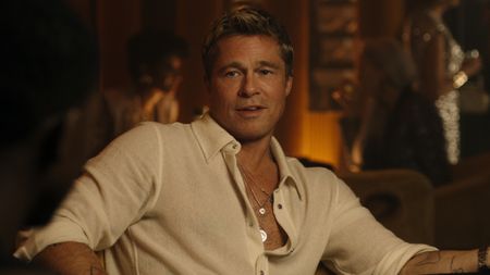 Brad Pitt sits smiling at the card table in F1.