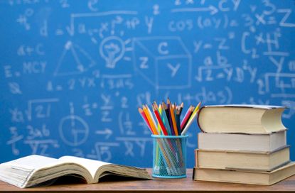 Back to school supplies. Books and blackboard on wooden background