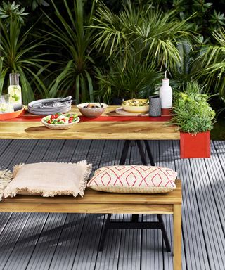 Al fresco dining area with outdoor bench, cushions, and red planter