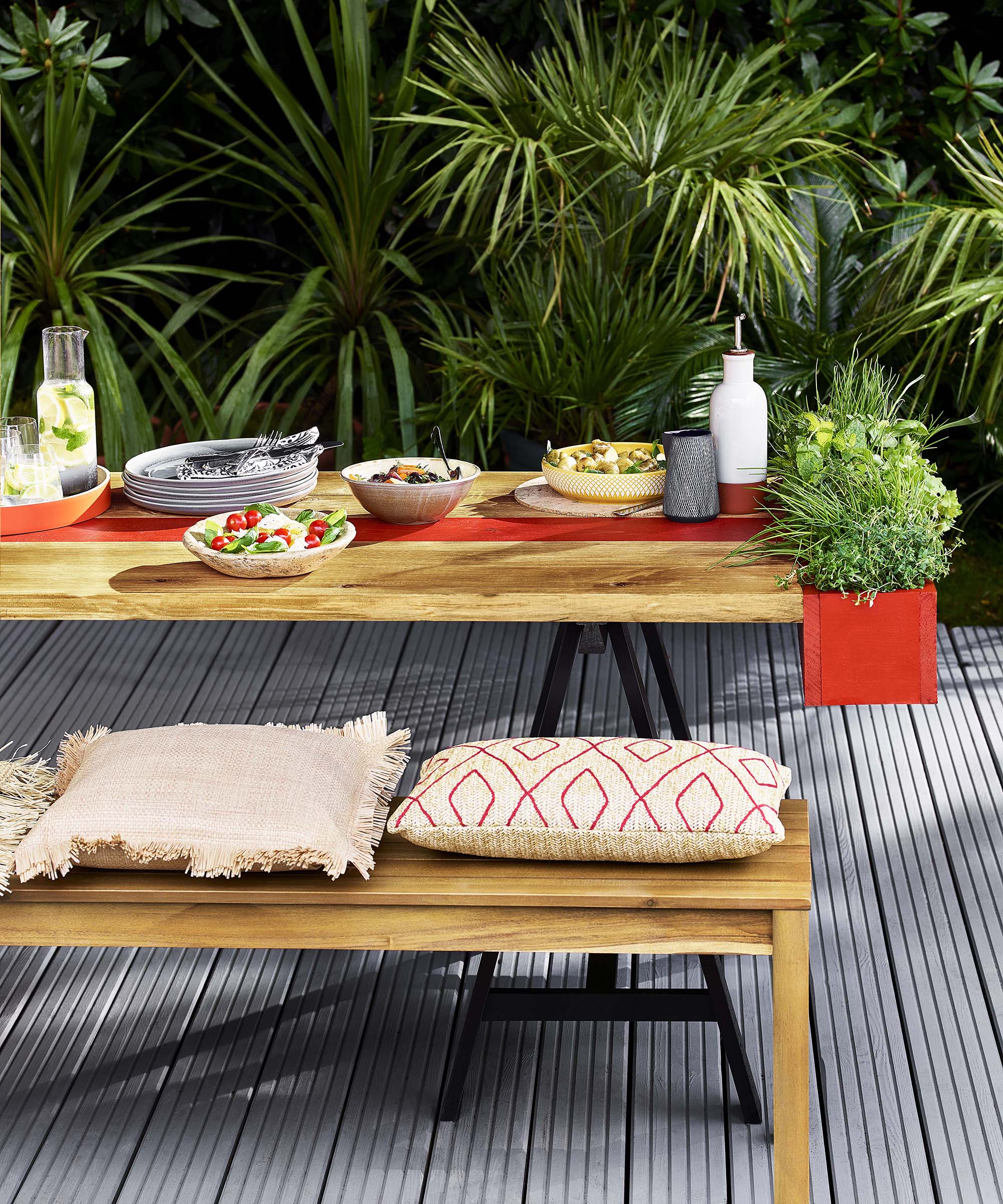 Al fresco dining area with outdoor bench, cushions, and red planter