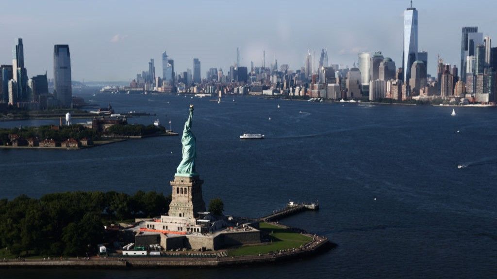 Aerial view of the Statue of Liberty with Manhattan&#039;s skyscrapers in the background.