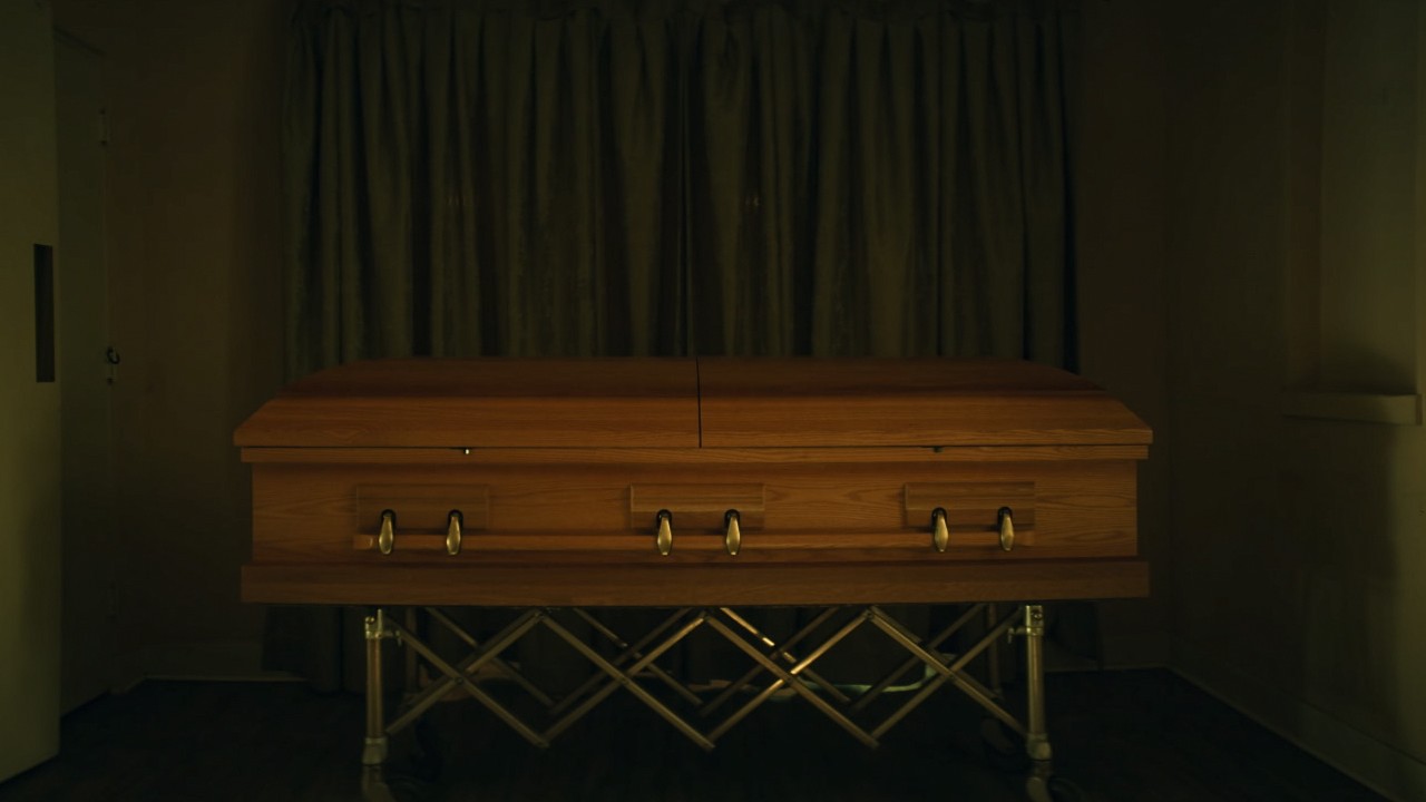 a picture of a casket with a green curtain behind it