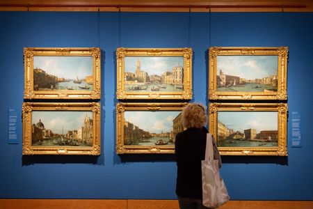 A woman stares at six paintings by Canaletto