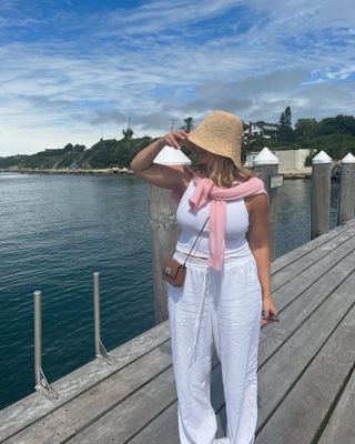 Summer rainy day outfits: @oliviamarcus wears a white tank top with linen trousers and a bucket bag