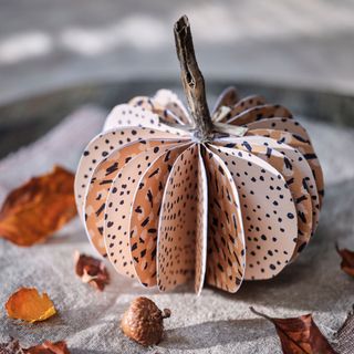 a paper pumpkin sitting on a piece of fabric