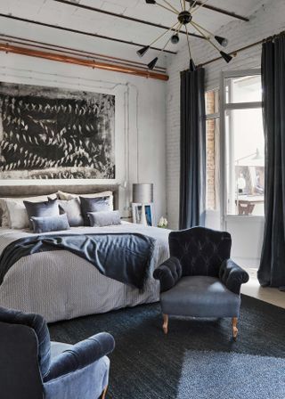 Grey and blue bedroom with high ceilings and velvet armchair