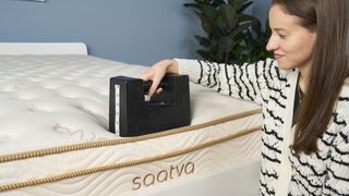 Our sleep staff writer tests the edge support of the Saatva Classic Mattress with a 25kg weight