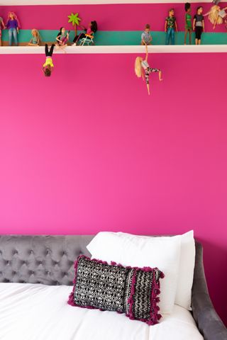 A pink wall with action figures suspended from the walls