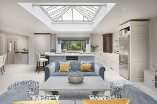 Open plan kitchen with roof lantern and neutral cabinetry and blue sofas