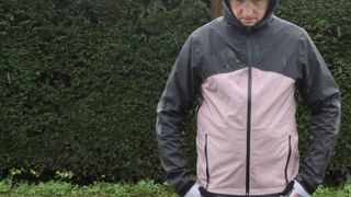 Man wearing cycling jacket in front of hedge