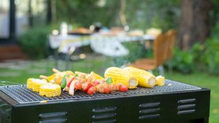 A basic charcoal grill with no lid or side tables grilling vegetables