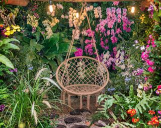 Woven hanging chair in backyard with lots of flowers