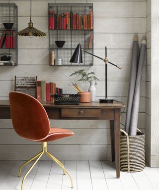 home office with wooden desk, metal shelving, dusky pink chair, black desk lamp and ceiling pendant