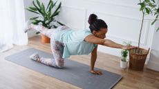 Woman performs bird dog abs exercise on yoga mat