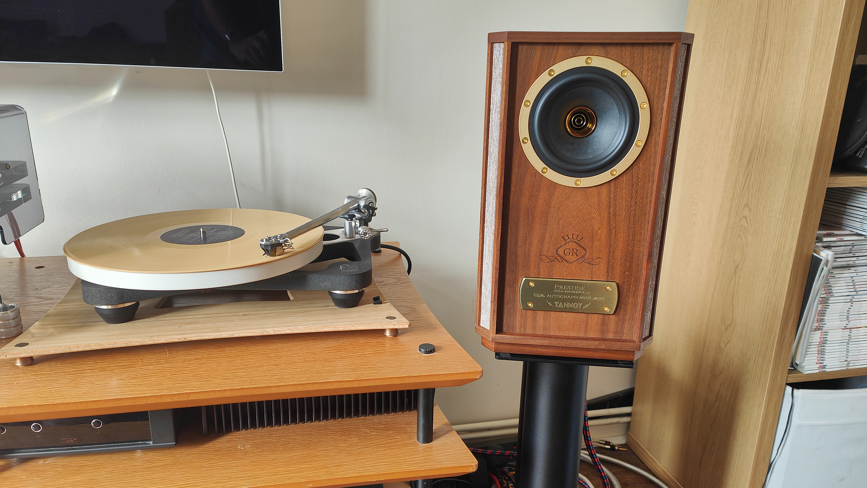 The Tannoy Autograph Mini pictured in a room next to a wooden sideboard and a record player