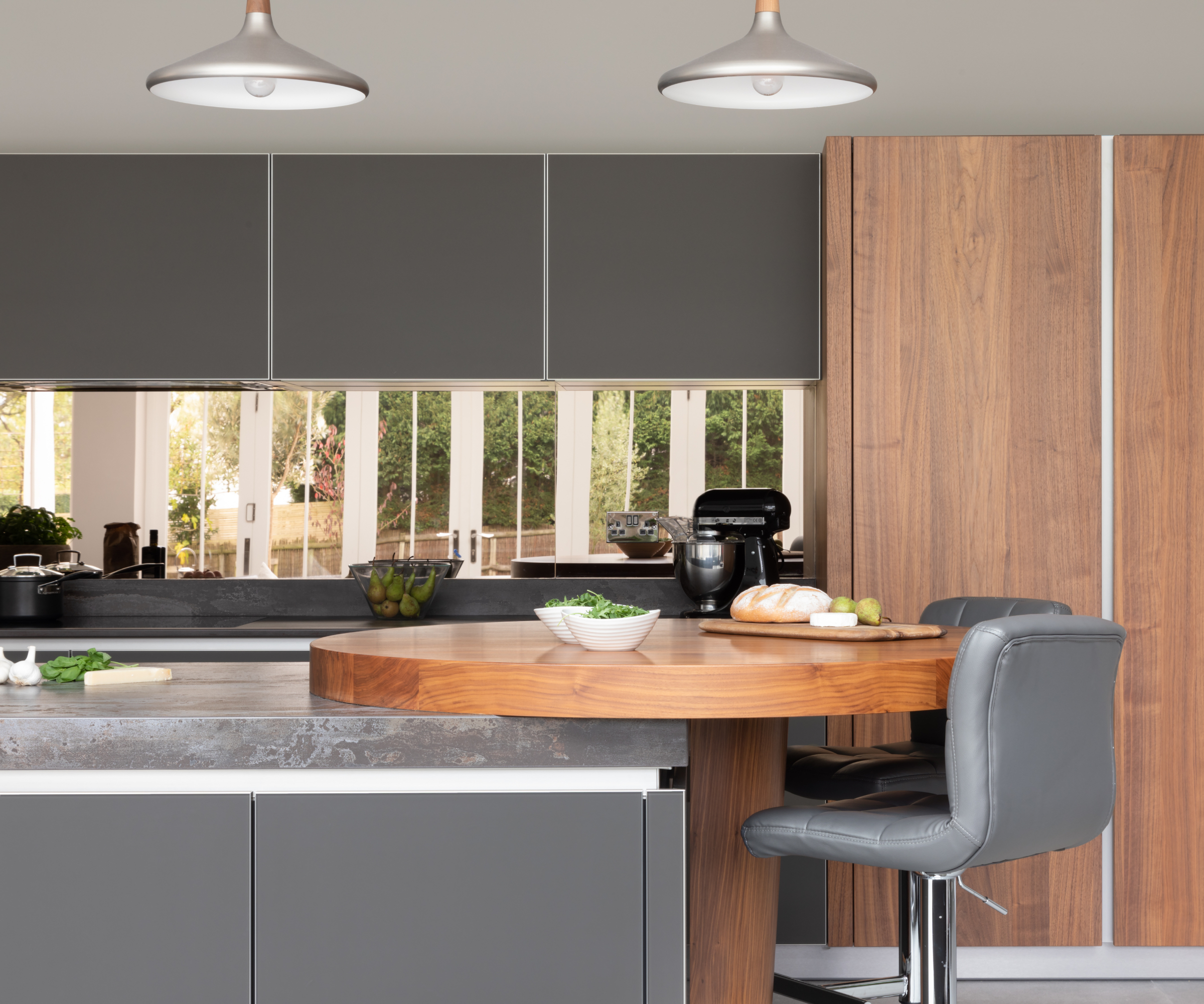 grey kitchen with dark wooden circular breakfast bar at end of island